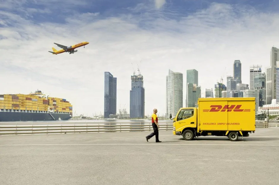 Statek, samolot, ciężarówka oraz pracownik firmy DHL na tle miasta